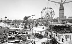 A panoramic view of the amusement park, which includes a Ferris wheel and a roller coaster (photographed in 1965)