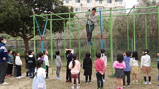 校庭の遊具の使い方を担任が自ら示しています