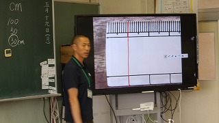 担任は大画面で㎜の単位を教え、子供たちに実際に測り取らせていました