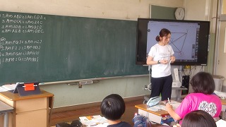 担任は、大画面で図形を映し出し、子供たちに対称となる頂点を意識させています