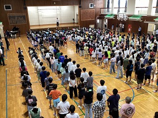 体育室で全校児童が校歌を合唱する様子