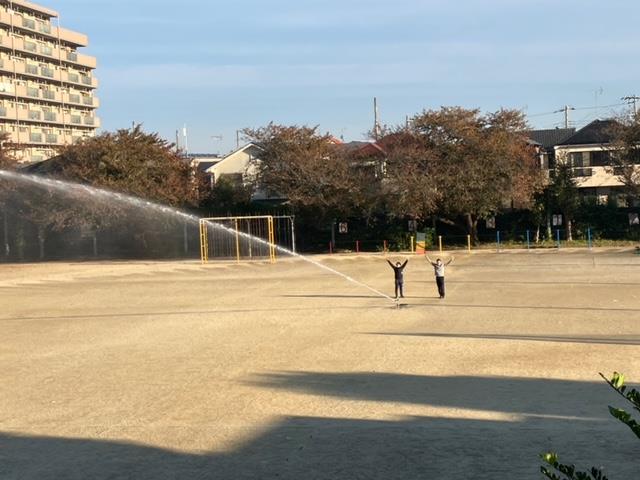 スプリンクラーで散水中(サッカー部の顧問2人)