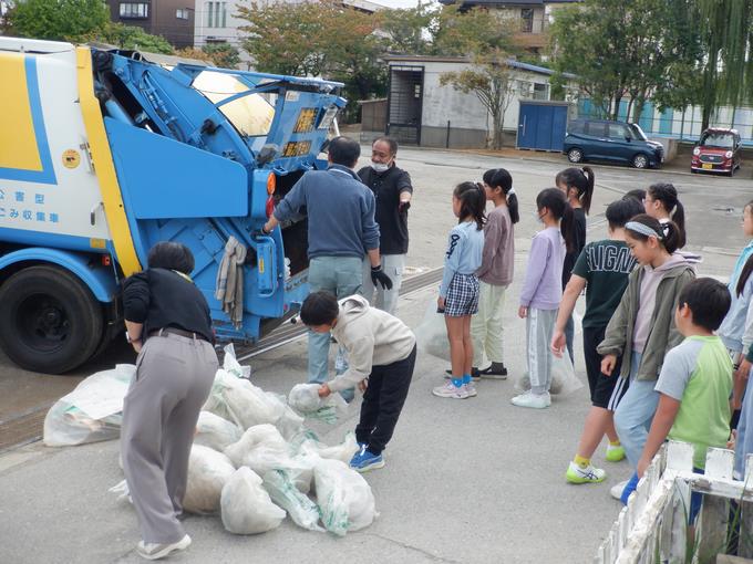 収集車にごみ袋を入れる体験