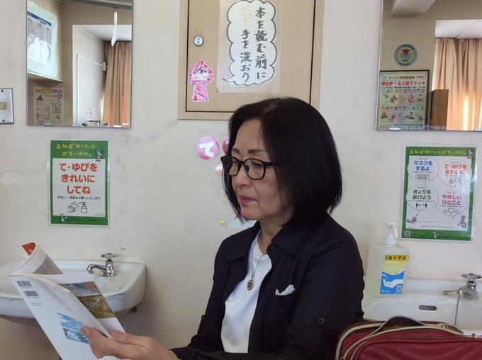 「エリカ」の掲載された道徳副読本を手に取る新井さん