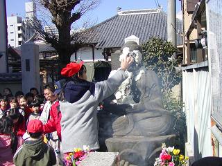 だいぶつにごはんをつける小学生