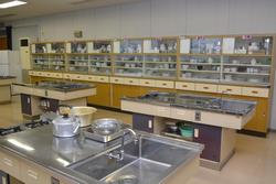 【家庭科室】使いやすい調理台が9台設置。冷蔵庫や電子レンジも設置され、快適な調理実習が行えます。