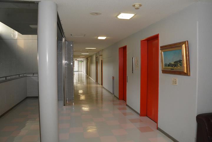 約30m続く2階廊下。右側には2基の赤いエレベータが設置されています。